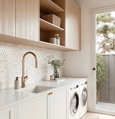 a washer and dryer in a room with wooden shelves on the wall above them