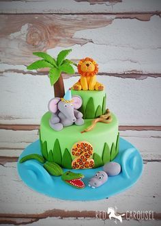 a three tiered cake decorated with animals and palm trees