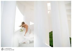 a woman in a wedding dress is sitting on the stairs and looking down at her bouquet