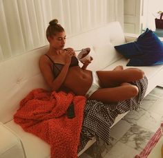 a woman sitting on a white couch eating food