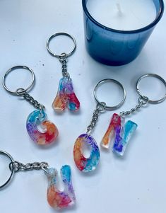 four keychains with different designs on them sitting next to a candle and glass container