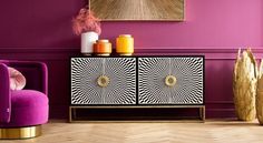 a living room with purple walls, gold accents and an art piece on the sideboard