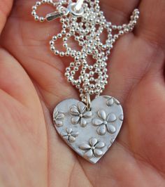 Heart flower necklace, floral heart pendant, mothers day pendant, garden necklace, embossed flower necklace, floral necklace, daisy necklace Floral heart pendant lovingly handcrafted in solid silver. The heart is decorated with a beautiful raised daisy flower pattern. It would make a stunning gift for mother's day or a gardener or just anyone who loves flowers. It is inspired by the beautiful flowers in my York wildlife garden. The pendant is hung on a sterling silver ball chain, finished with a sterling silver clasp. The pendant is approximately 2cm by 1.8cm. All my nature jewellery raises funds to support my hedgehog hospital caring for poorly and injured wild hedgehogs.  Your pendant will be gift boxed and tied with pretty ribbon. I also enclose a rescue hedgehog postcard and informatio Flower Charm Pendant Necklace Gift For Mom, Flower Charm Necklace As Gift For Mom, Pendant Necklace With Flower Charm For Mom, Heart-shaped Flower Charm Jewelry For Mother's Day, Handmade Flower Pendant Charm Necklace For Mother's Day, Mother's Day Flower Shaped Jewelry With Heart Charm, Mother's Day Flower Pendant Charm Necklace, Mother's Day Flower Jewelry With Heart Charm, Mother's Day Jewelry With Heart Charm And Flower Shape