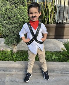 a young boy wearing a costume with suspenders and a fake moustache