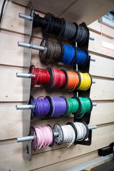 there are many different colors of wires in the holder on the wall behind the rack