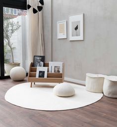 a living room with white furniture and pictures on the wall, along with wooden flooring