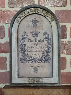 an old sign on the side of a brick wall in front of a wooden shelf