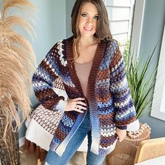 a woman standing in a room wearing a multicolored cardigan