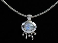 "This unique oval Rainbow Moonstone necklace is handcrafted with a hammered texture and dangles, giving it a bohemian vibe. It's the perfect addition to any jewelry collection, offering a unique and elegant design that is both stylish and timeless. The centerpiece of the pendant is a shimmering oval Rainbow Moonstone and each one is unique. The stone is set in a Sterling Silver bezel with a hammered texture that adds a touch of rustic charm to the piece. Delicate Sterling Silver dangles hang from the bottom, adding movement and intrigue to the design. The handmade chain is adjustable, allowing you to customize the length. Rainbow Moonstone is believed to have powerful healing properties, promoting emotional balance, protection, and inner peace. Wearing this necklace is a meaningful way to Sterling Silver Boho Necklace, Silver Boho Necklace, Hammered Pendant, Rainbow Moonstone Jewelry, Rainbow Moonstone Necklace, Bohemian Necklace, Vermeil Jewelry, Moonstone Necklace, Moonstone Jewelry