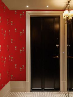 two black doors in front of a red wall with white and gold designs on it