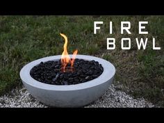 a fire bowl sitting on top of gravel in the middle of a grass covered field