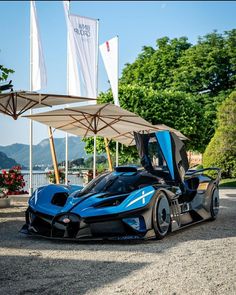 a blue and black sports car parked in front of a building with flags on it