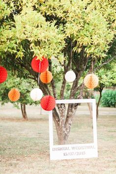 a tree with paper lanterns hanging from it's branches in front of a photo frame