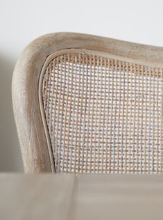 a close up view of a wooden chair with wicker back and seat cushioning