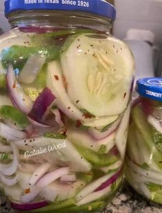 two jars filled with pickles and onions sitting on a counter next to each other