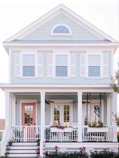 a white house with flowers in the front yard and steps leading up to the porch