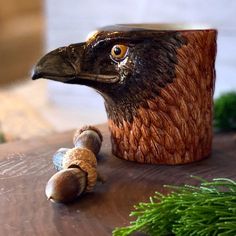 a close up of a bird figurine on a table next to a pine cone