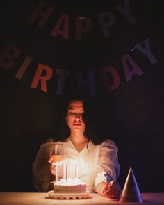 a woman sitting at a table in front of a birthday cake with candles on it