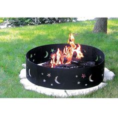 an outdoor fire pit in the grass with stars and moon designs on it's sides