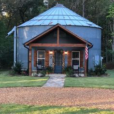 a blue round building with an american flag on the front door and two chairs at the entrance