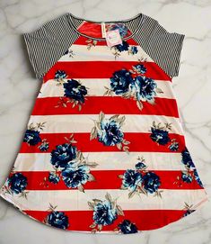 This red, white, and blue floral top is perfect for celebrating Memorial Day, 4th of July, Labor Day and any other day! Stand out this Summer in our cute plus size tunic – it's longer length and soft, stretchy fabric makes it ideal for curvy women to feel confident and comfortable! Don't miss your chance to show your American pride in style. Make this your favorite holiday and be ready for the fireworks, and compliments, to fly! Boom! Striped Shirt Details: 1xl: 44" Chest 30" Length 2xl: 46" Che Spring Striped Tops With Floral Print, Striped Floral Print Tops For Summer, Red Floral Print T-shirt For Summer, Red Short Sleeve Tops With Floral Print, Red Short Sleeve Top With Floral Print, Red Floral Print Short Sleeve Tops, Relaxed Fit Red Top With Floral Print, Red Floral Print Short Sleeve T-shirt, Red Floral Print Cotton T-shirt