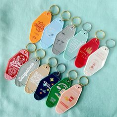 six key chains with different colored tags attached to them on a blue cloth covered surface