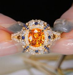 * Condition: Brand new * Center Stone: Natural Spessartite Fanta Garnet, Oval Brilliant cut, Approx 2.29ct * Side stones:  Natural White Diamond, Round-cut, Marquise cut (VVS clarity with F color) Natural Blue Sapphire, Round-cut * Two in one jewelry, can use on ring or pendant. * Metal Purity: 18k Solid Yellow Gold (optional) * Chain Length: 45cm (adjustable) * Free DHL Express Shipping. * Attached with Certificate.  * Each piece is made-to-order with care and special attention to detail.  all Orange Round Yellow Sapphire Jewelry, Luxury Orange Gemstone Ring, Luxury Yellow Oval Jewelry, Orange Round Jewelry With Brilliant Cut, Luxury Yellow Baguette Cut Jewelry, Orange Fine Jewelry With Halo Setting, Luxury Orange Yellow Sapphire Jewelry, Luxury Yellow Sapphire Jewelry, Luxury Orange Jewelry With Yellow Sapphire