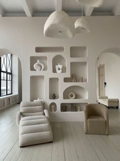 a living room filled with lots of white furniture and shelves on the wall next to each other