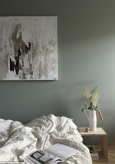 a bed with white sheets and a painting on the wall above it in a bedroom