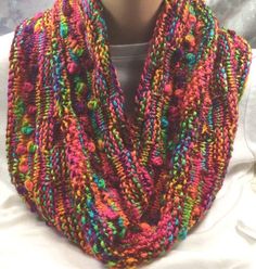 a close up of a person wearing a multicolored knitted scarf