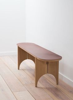 a wooden bench sitting on top of a hard wood floor next to a white wall