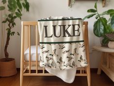 a baby crib with a blanket that says luke on it and birds in the background