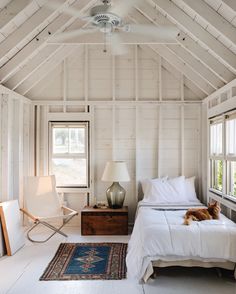 a bedroom with white walls and wooden ceiling