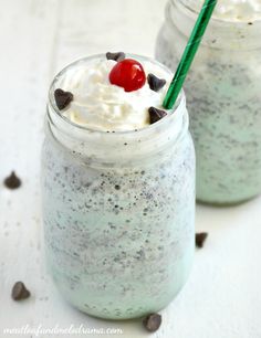 two mason jars filled with ice cream and topped with a cherries garnish