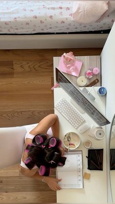 a woman sitting at a desk in front of a laptop computer with her hair tied back