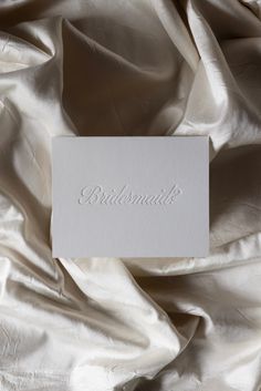 a white card with the word diamond on it laying on top of a satin fabric