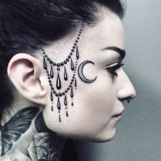 a woman with tattoos on her face and neck is looking to the side while wearing a chain