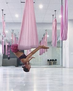 a woman doing a handstand on a hammock in an empty room