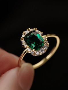 a person holding a green ring with diamonds on it