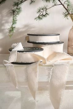 three white hats with black rims on top of a table next to a vase