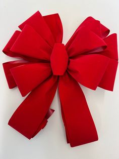 a close up of a red bow on a white surface