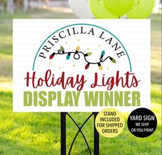 a sign that says holiday lights display winner in front of some balloons on the grass