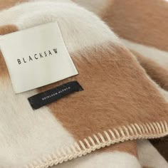 a label on the back of a brown and white checkered coat that says blacksaw