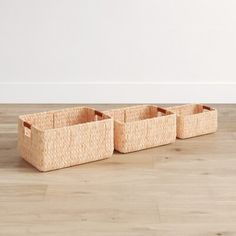 three woven baskets sitting on top of a wooden floor