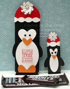 a penguin with a santa hat next to some chocolate bar wrappers on a table