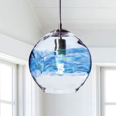 a light fixture hanging from the ceiling in a room with windows and blue water inside