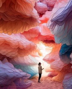 a person standing in the middle of a tunnel filled with colorful paper mountains and clouds