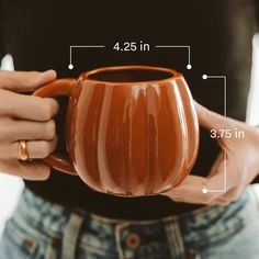 a close up of a person holding a coffee cup with measurements on the front and side