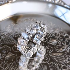 two wedding rings sitting on top of a silver platter with ornate designs around it