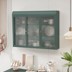 a green cabinet is hanging on the wall above a desk with other items and decorations